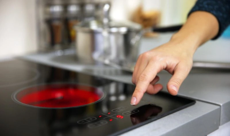 Pessoa ajustando os controles de um cooktop 5 bocas com mesa de vidro